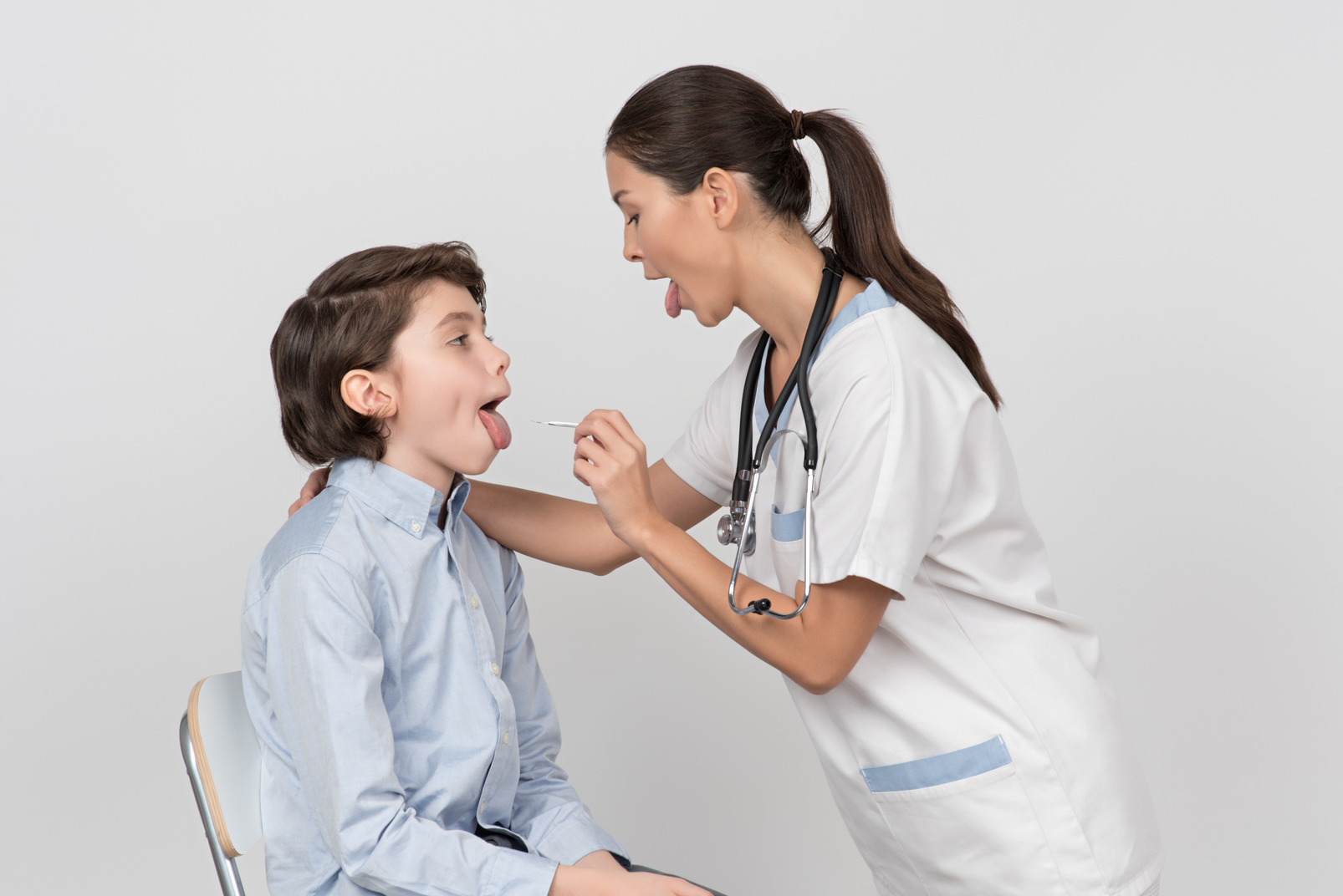 Female doctor showing her tongue out and examining her patient's mouth