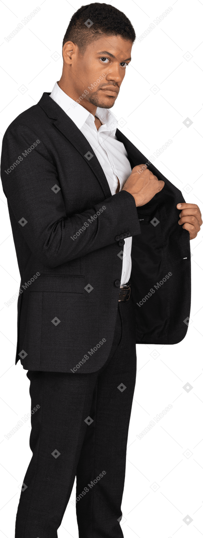 Vue latérale d'un jeune homme en costume noir mettant quelque chose dans la poche