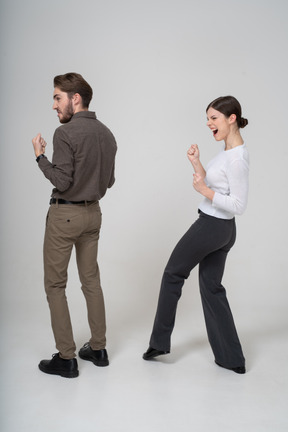 Vue arrière de trois quarts d'un jeune couple ravi en vêtements de bureau