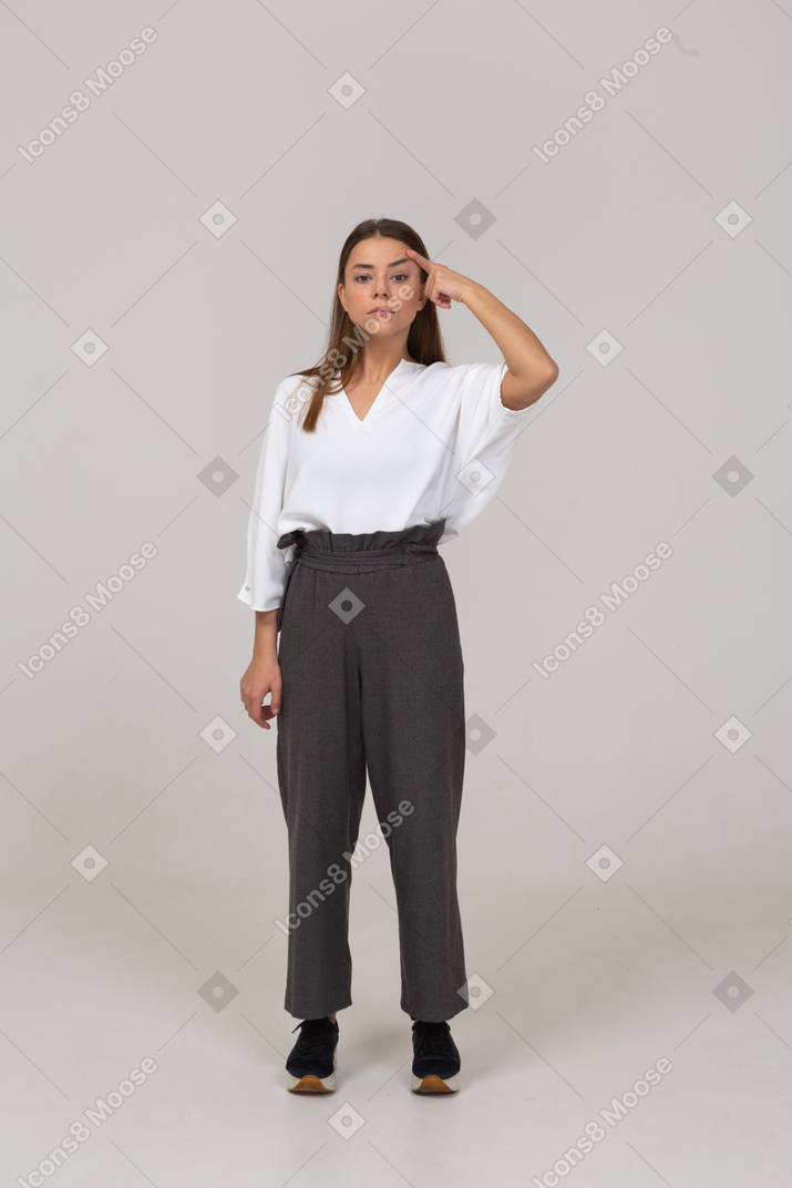 Vue de face d'une jeune femme en vêtements de bureau regardant la caméra et touchant la tête