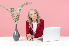 Aged office worker sitting at the table with laptop