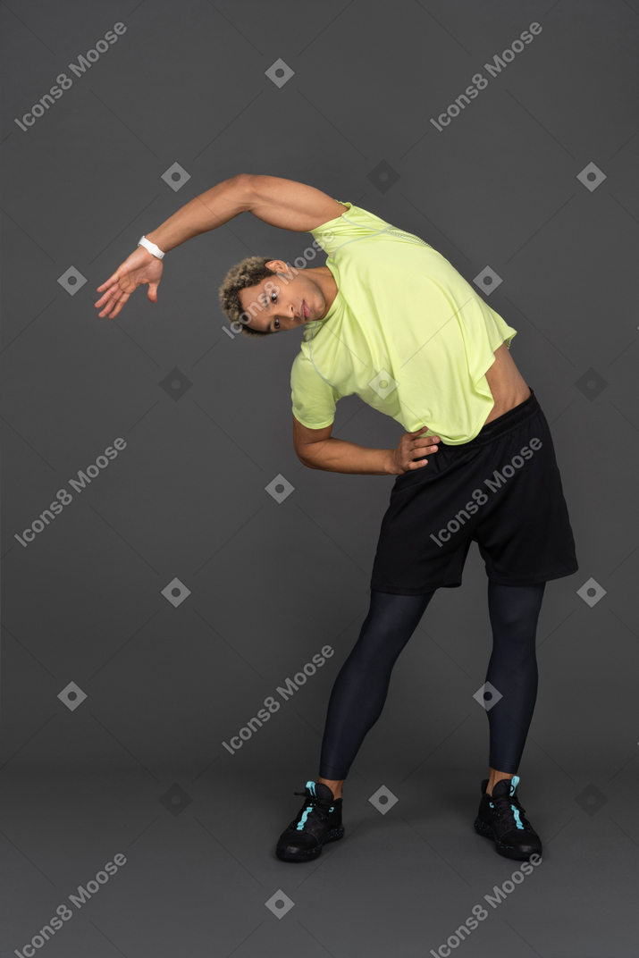 Sporty dark skinned man doing side bends