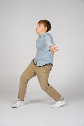 A young boy walking with his arms stretched out