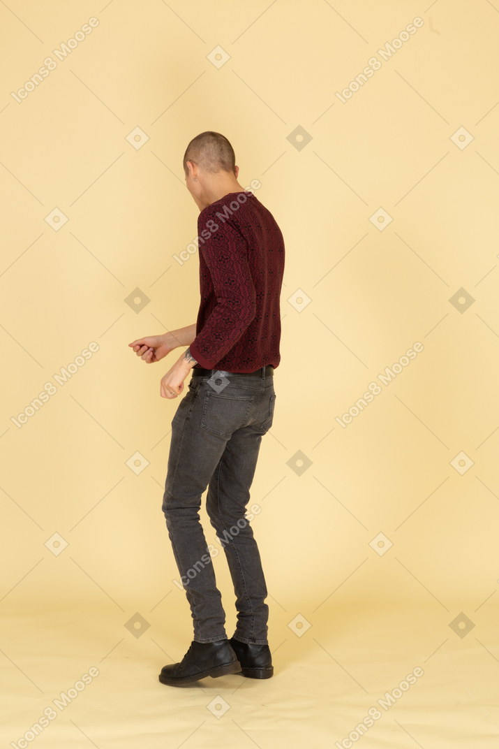 Vista posteriore di tre quarti di un giovane che balla in pullover rosso