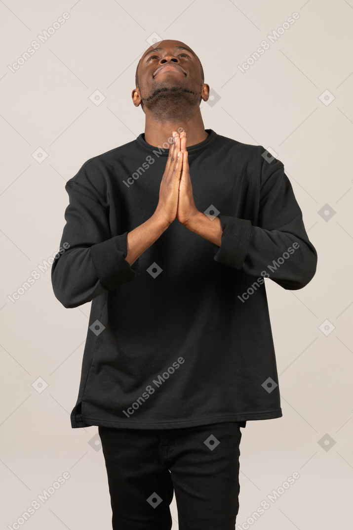 Young man looking up with praying hands