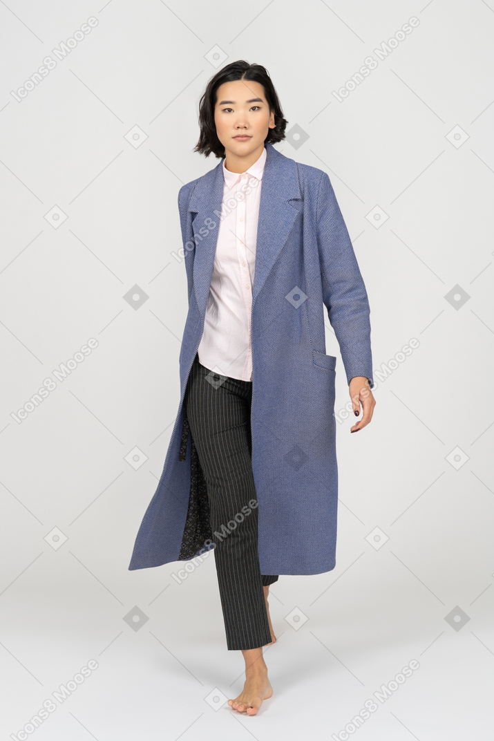 Уверенная в себе женщина в пальто ходит босиком