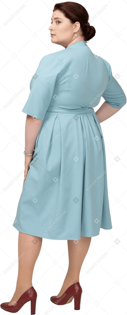 Vista traseira de uma mulher de vestido azul posando com a mão no quadril