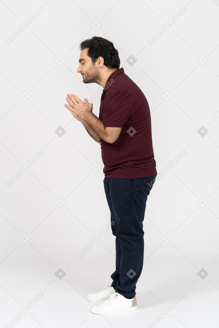 Vista lateral de un hombre rezando con los ojos cerrados