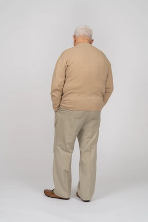 Rear view of an old man in casual clothes standing with hands in pockets