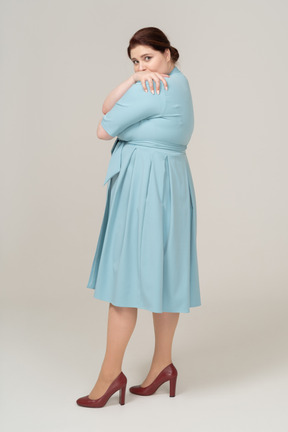Вид сбоку на женщину в синем платье, обнимающуюся