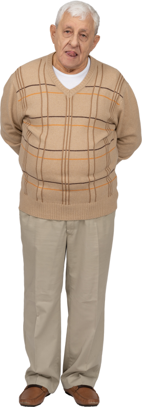 Vista frontal de um velho em roupas casuais, mostrando a língua