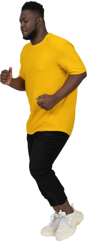 Three-quarter view of a running young dark-skinned man in yellow t-shirt