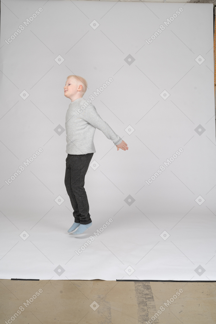 Side view of a little boy jumping up