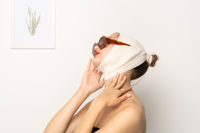 包帯を巻いた頭とサングラスを持つ女性の側面図