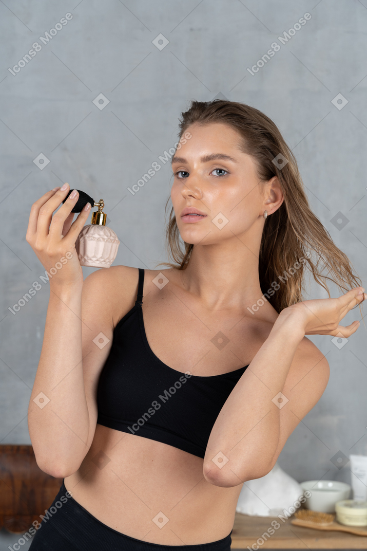 Attractive young woman spraying perfume on her hair