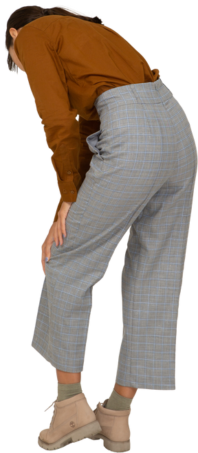 Vista posteriore di tre quarti di una giovane donna asiatica in calzoni e camicetta protesa in avanti