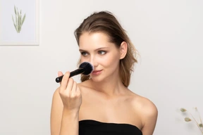Front view of a young woman applying powder on her nose