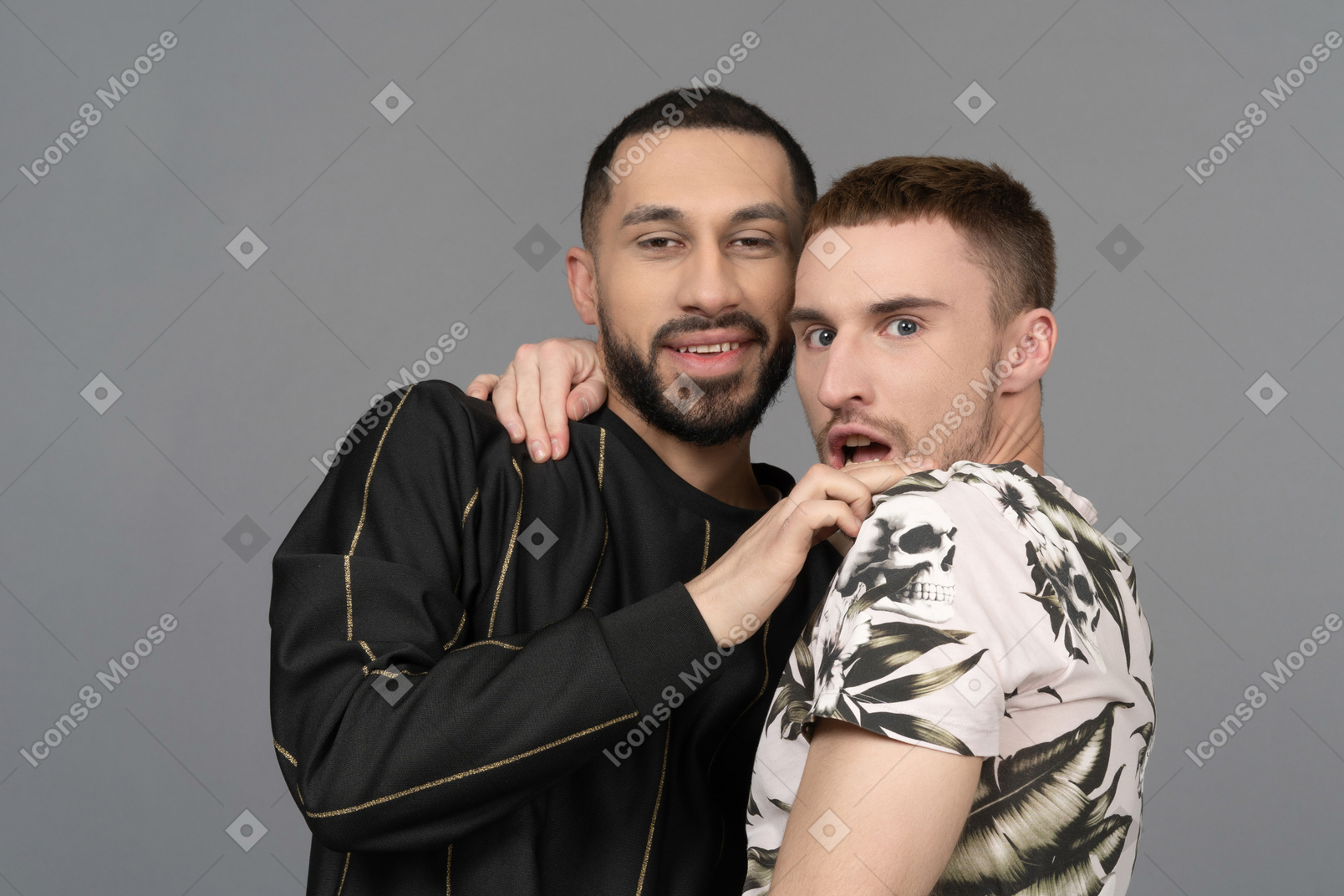 Portrait of a young male couple looking at camera one with a smile and another with a shocked expression
