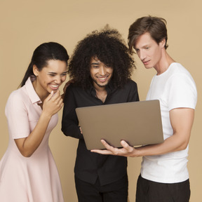 Gesellschaft von freunden, die etwas auf dem laptop suchen und lachen