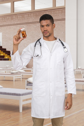 A man in a white lab coat holding a jar of pills