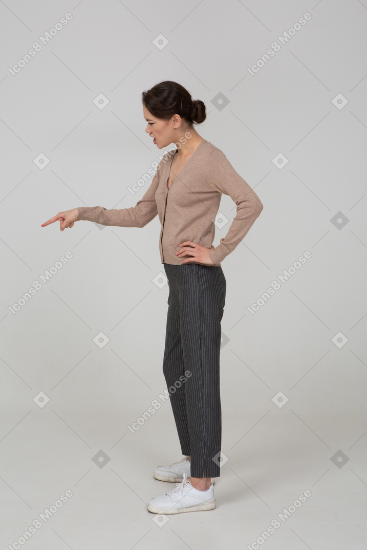 Side view of a furious young lady in beige pullover pointing finger