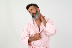 Mature man with disgusted facial expression touching his neck