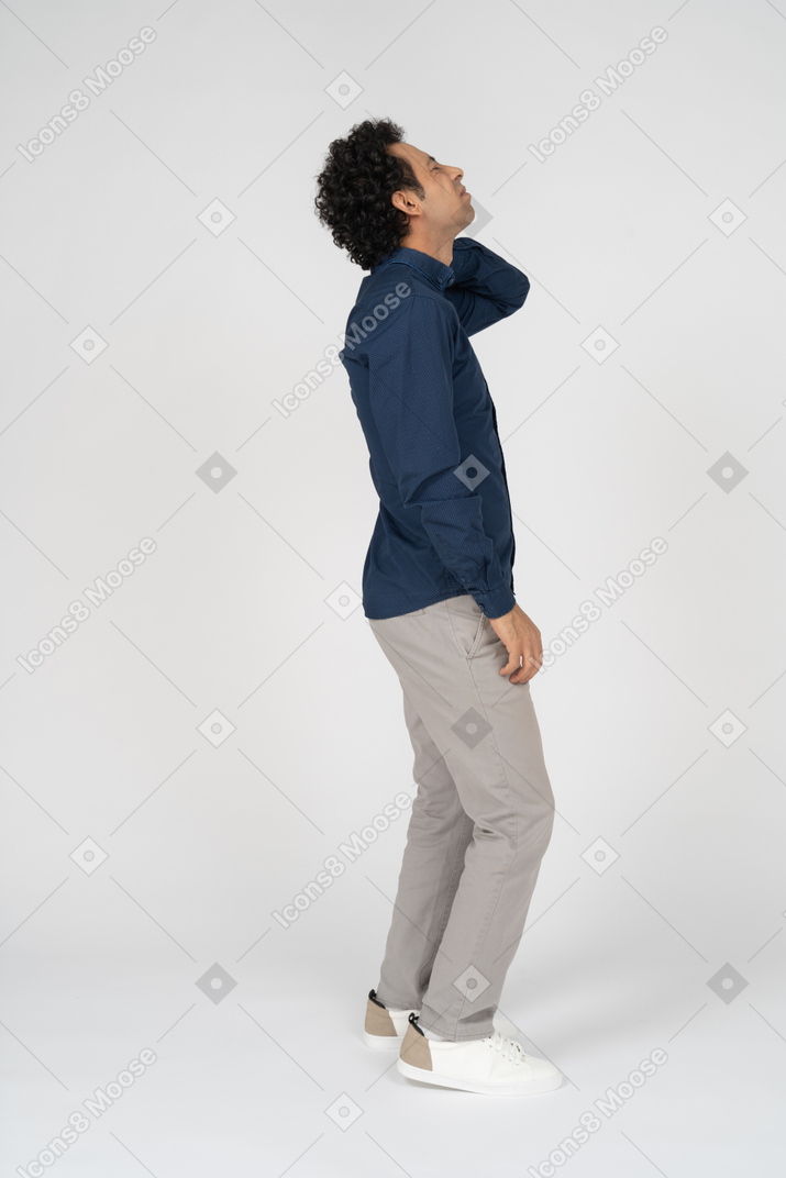 Side view of a man in casual clothes suffering from pain in neck