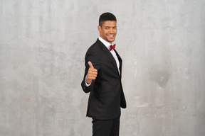 Cheerful man in black suit giving thumbs up