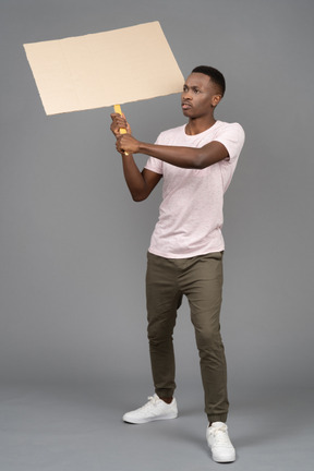 A serious young man holding a blank poster