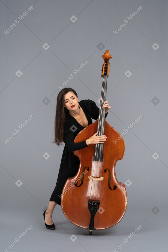 Front view of a young woman in black dress playing the double-bass and looking down