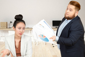 A male colleague showing papers with graphs to a female colleague