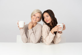 Mujeres jóvenes abrazando y bebiendo café