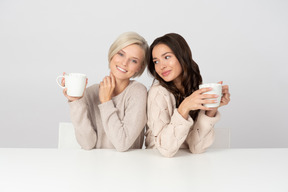 Junge frauen, die sich umarmen und kaffee trinken