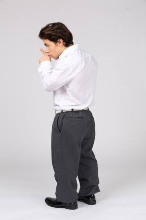 Side view of businessman showing silence gesture