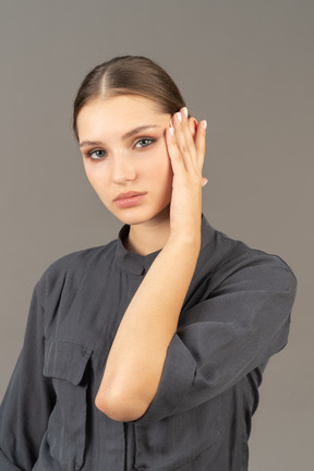 Vista de tres cuartos de una mujer joven en un mono quitando el maquillaje