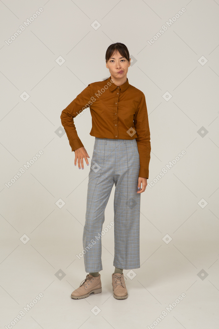 Front view of a pouting young asian female in breeches and blouse putting hand on hi