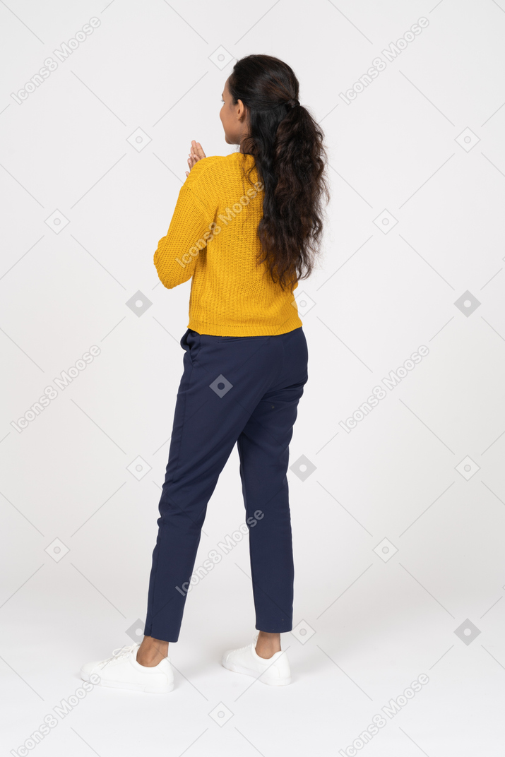 Vista posteriore di una ragazza in abiti casual che fa un gesto di preghiera