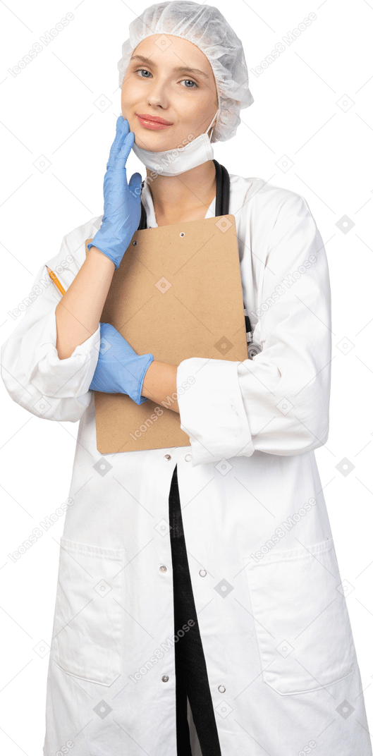 Vista frontal de una joven doctora complacida sosteniendo un lápiz y una tableta y tocando la cara