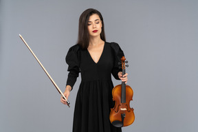 Primo piano di una giovane donna in abito nero che tiene il violino e l'archetto