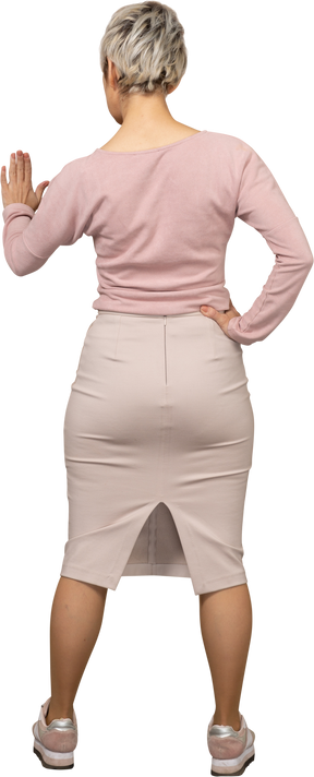 Vista traseira de uma mulher com roupas casuais mostrando um gesto de pare