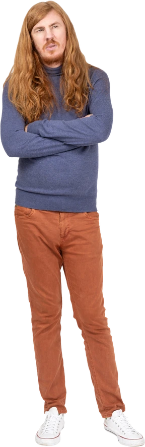 Front view of a thoughtful young man standing with crossed arms