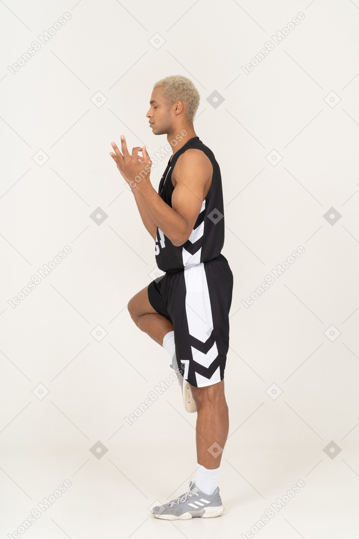 Side view of a meditating young male basketball player