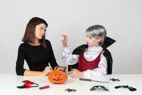 Menino em vampiro olhar mostrando dentes de vampiro falsos a mãe