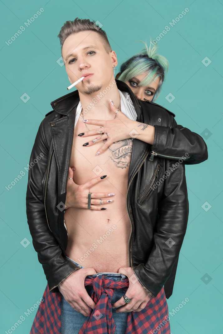 Smoking punk and his girlfriend standing against camera