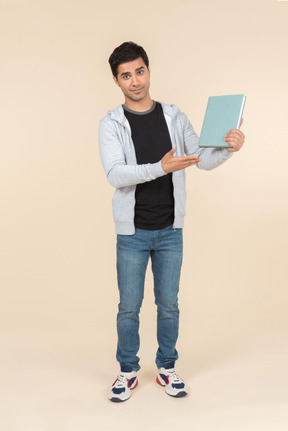 Young caucasian man pointing at book he's holding