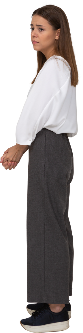 Side view of a sad young lady in office clothing holding hands together