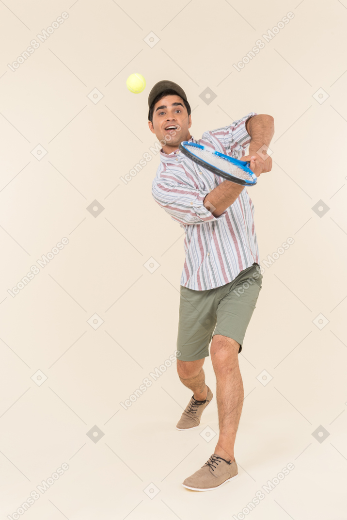 Young caucasian guy throwing ball with tennis racket