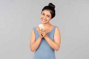 Smiling young indian woman holding cosmetic bottle