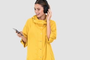 Femme en imperméable jaune écoutant de la musique