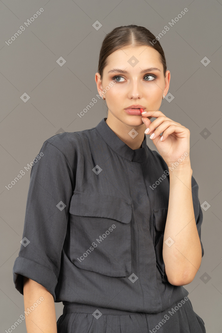 Front view of a young woman in a jumpsuit taking pill